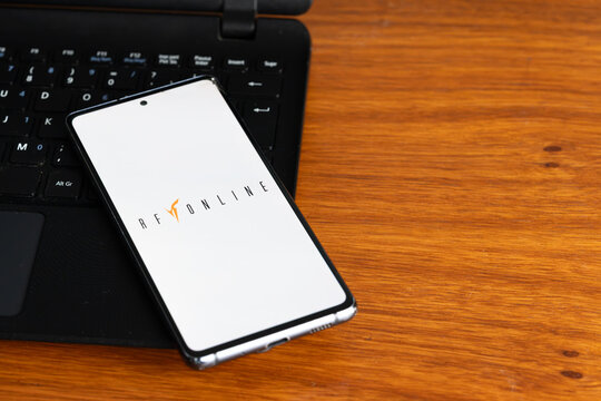 Punta Arenas, Chile &ndash; July 2, 2026: The RF Online video game logo displayed on a smartphone screen resting on a laptop keyboard over a wooden table background