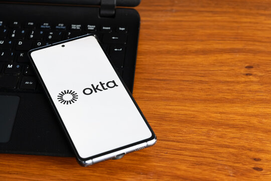 Punta Arenas, Chile &ndash; July 3, 2026: The Okta logo displayed on a smartphone screen resting on a laptop keyboard over a wooden table background