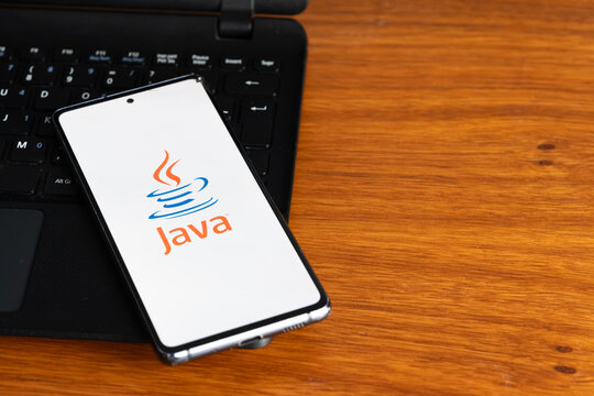Punta Arenas, Chile &ndash; July 7, 2026: The Java programming language logo displayed on a smartphone screen resting on a laptop keyboard over a wooden table background