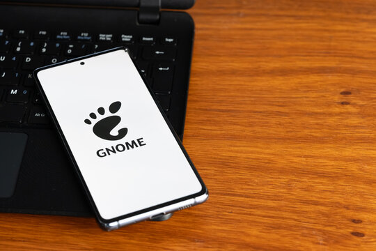 Punta Arenas, Chile &ndash; July 7, 2026: The GNOME desktop environment logo displayed on a smartphone screen resting on a laptop keyboard over a wooden table background