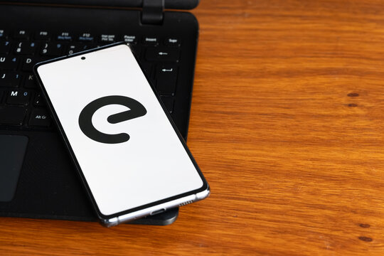 Punta Arenas, Chile &ndash; July 8, 2026: The Enel multinational energy company logo displayed on a smartphone screen resting on a laptop keyboard over a wooden table background
