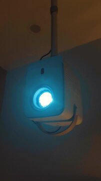 Modern projector mounted on a ceiling, displaying a bright blue beam of light, symbolizing contemporary home entertainment, multimedia technology, and a smart living environment