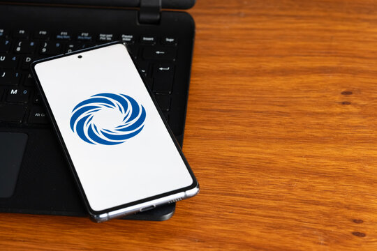 Punta Arenas, Chile &ndash; July 8, 2026: A close-up of a mobile phone showcasing the blue multi-layered swirl emblem of CloudLinux software, placed on top of a black laptop on a wooden desk