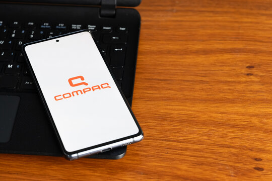 Punta Arenas, Chile &ndash; July 8, 2026: The Compaq computer brand logo displayed on a smartphone screen resting on a laptop keyboard over a wooden table background