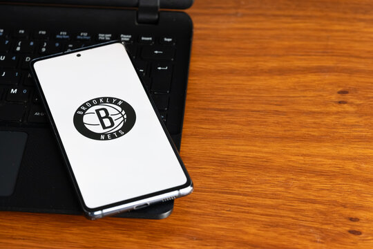 Punta Arenas, Chile &ndash; July 8, 2026: The Brooklyn Nets NBA basketball team logo displayed on a smartphone screen resting on a laptop keyboard over a wooden table background