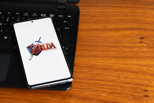 Punta Arenas, Chile &ndash; July 9, 2026: The Legend of Zelda: Ocarina of Time video game logo displayed on a smartphone screen resting on a laptop keyboard over a wooden table background