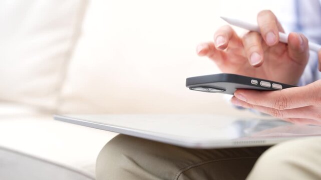Person using smartphone while holding stylus pen above digital tablet. Mobile communication,Online business,Digital connectivity,Remote work,Fintech application and modern technology lifestyle