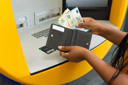 Person holding euro banknotes and wallet at atm