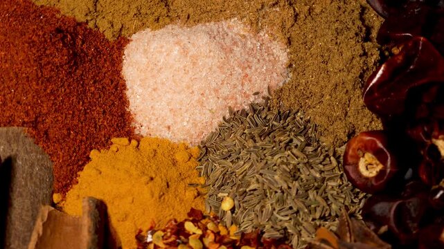 Assortment of aromatic culinary herbs and ground spices spinning close up