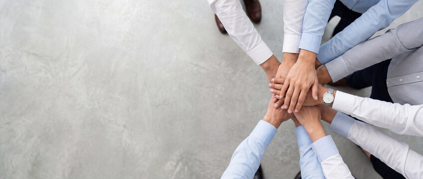 Teamwork and unity shown by a group of diverse business people stacking hands together in a circle, symbolizing collaboration and success in a modern office setting, useful for secure