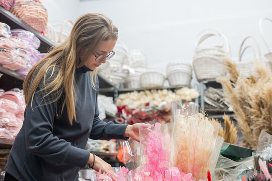 A Caucasian woman buys dried flowers at a home decor store.
