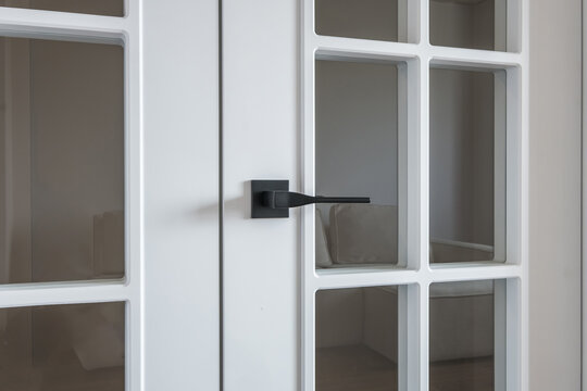door handle on white wooden door in interior. Knob close-up elements. Door handle, fittings for interior design