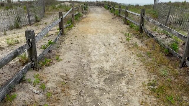 Tilt up view of a sandy path to the beach with a spit rail wooden fence
