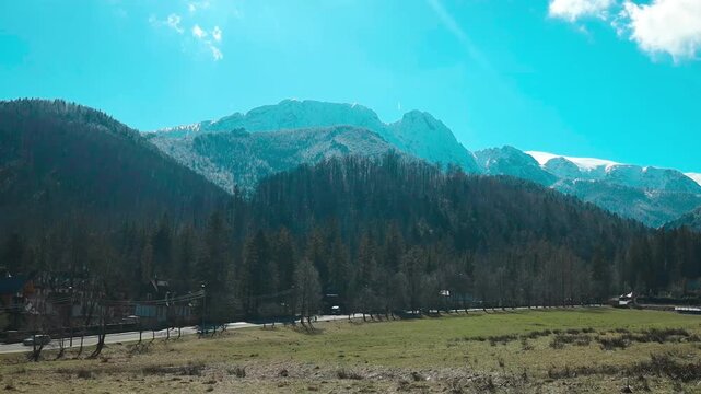 A tranquil mountain landscape featuring expansive open fields and rugged rocky terrain, captured from a wide-angle perspective. This scene is travel, nature, and landscape content.