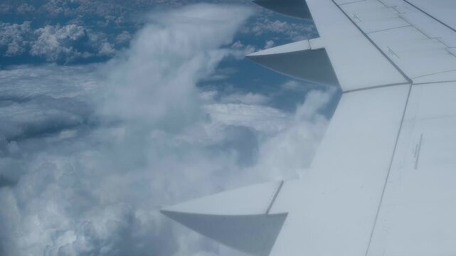 Airplane wing flying through beautiful white clouds
