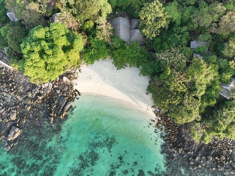 Aerial view of Koh Khai Nok featuring a white sand beach, turquoise waters with coral reefs, and lush tropical vegetation in Phru Nai, Phang Nga, Thailand.