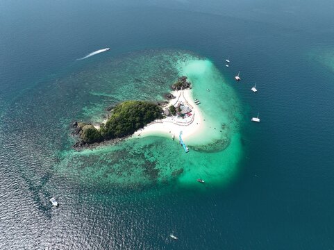 Aerial view of Koh Khai Nok island featuring white sandy beaches, turquoise waters, coral reefs, and anchored boats in the Andaman Sea, Phru Nai, Phang Nga, Thailand.