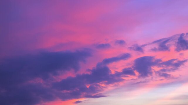 Morning or evening sky. Colorful clouds fill twilight with gradients of purple and pink during sunset or sunrise. Natural background. Beauty in nature. Expressive cloudscape. High quality 4K footage.