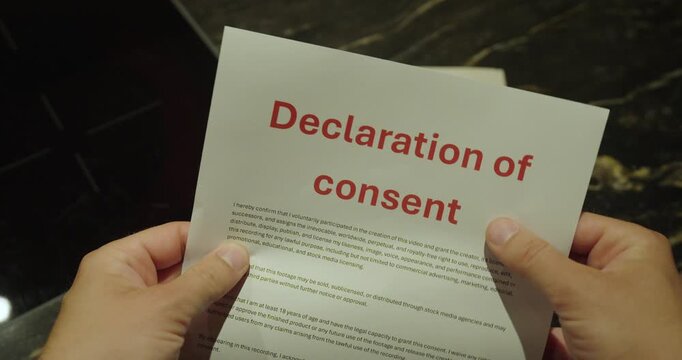Close-up of a person holding a declaration of consent document. Concept of legal consent, agreements, paperwork, compliance, and authorization.