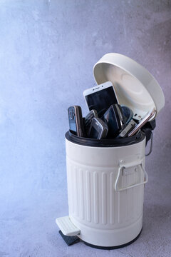 Mobile phones discarded in a trash bin as a symbol of electronic waste and technologi-cal obsolescence