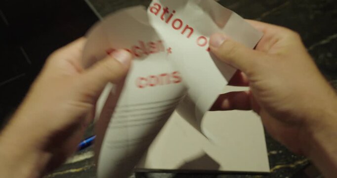 Close-up of a person tearing up a declaration of consent document with both hands. Concept of withdrawing consent, canceling authorization, legal documents, and personal rights.