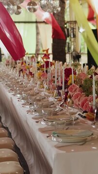 Vertical video. Wedding banquet table under outdoor tent with hanging fabric drapery decorations.
