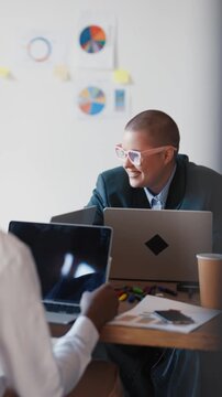 Working day in office, adult male and female coworkers communicating, teamwork. Office workers talking about work sitting at table in room for business meeting, marketing and financial professionals