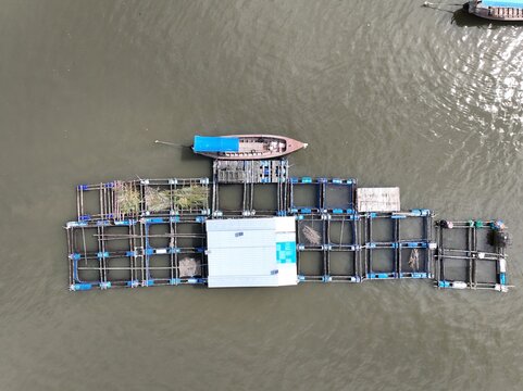 Aerial view of a floating fish farm structure with wooden frames and nets moored in the water at Ko Panyi, Phang Nga, Thailand.