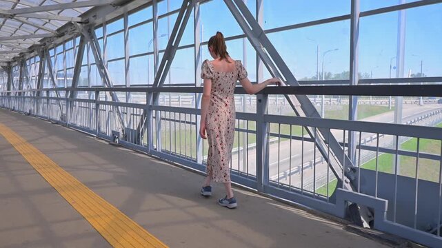 A Caucasian woman with cerebral palsy walks across a pedestrian bridge.