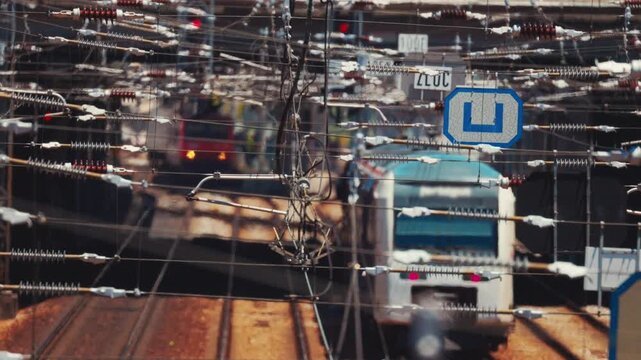 Commuter train approaching station through tangled railway catenary wires
