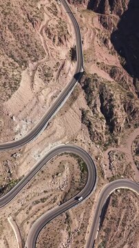 Drone vertical video of mountain road curves above turquoise Potrerillos lake in Mendoza, Argentina