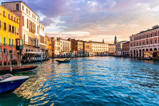 romantic view of a canal in Venice with boats and blue water and beautiful vintage buildings around the cityscape