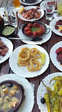 Traditional Spanish tapas variety on a wooden table including calamari and meatballs