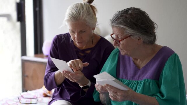 Daughter spends time with her mother at a senior care home sharing stories and looking at old photos in a warm setting