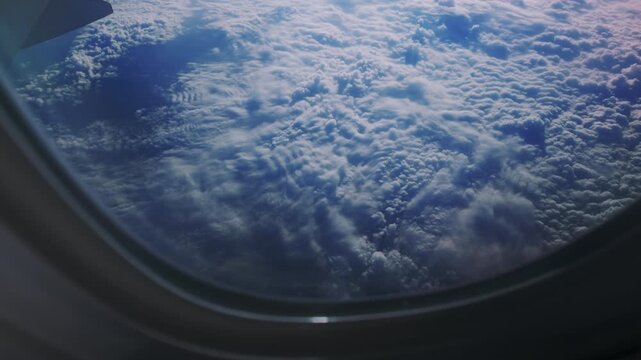 Clouds seen from an airplane window during daytime flight over the sky at a high altitude above the earth