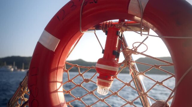 Lifebuoy with lantern on a boat in the water at sunset near a rocky coastline