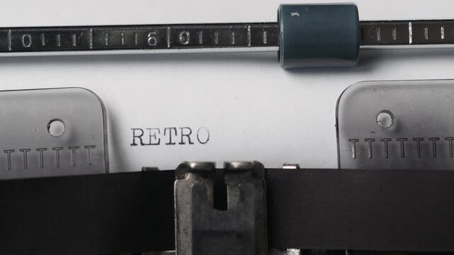 Typewriter prints the word retro on paper showing vintage writing tools in use