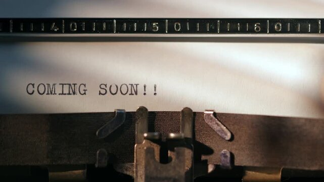 Typewriter shows text that says coming soon, showing upcoming project or announcement on a white page