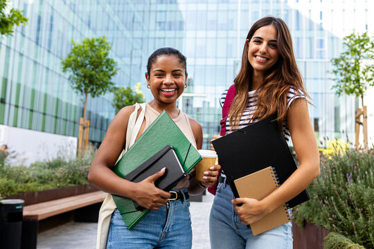 Happy diverse female students walking together on campus