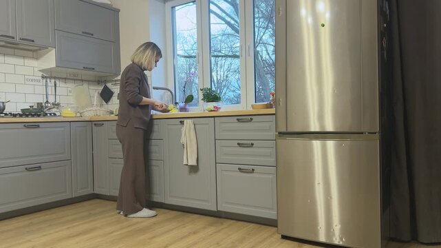 Woman slicing raw potatoes into thin pieces for soup cooking. Home kitchen meal preparation routine.