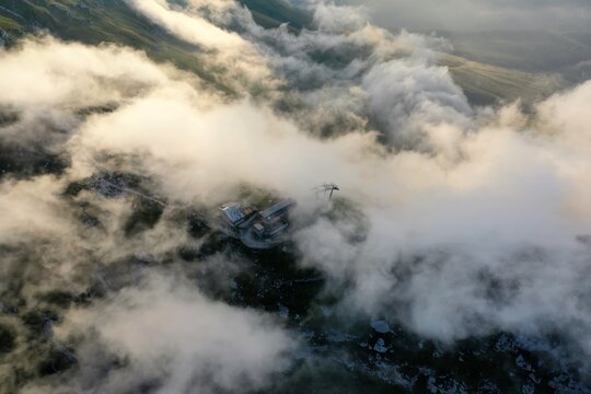 Aerial view of Corno Piccolo partially obscured by thick clouds over the rocky terrain and mountain infrastructure of Pietracamela, Abruzzo, Italy.
