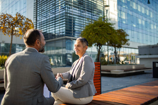 Two business professionals shaking hands outside modern office building