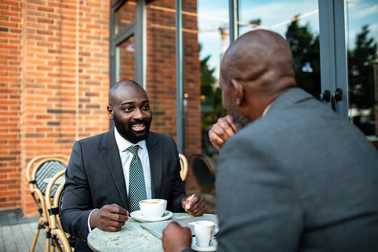 Two businessmen meeting over coffee at an outdoor cafe