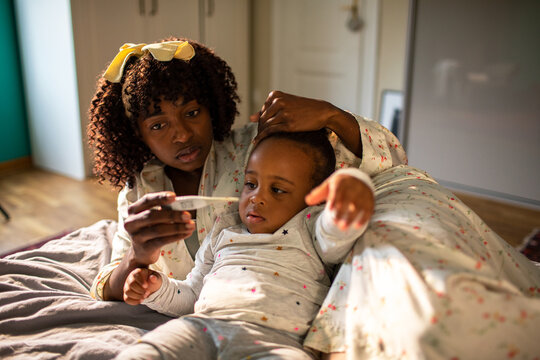 Concerned parent checking toddler's fever at home