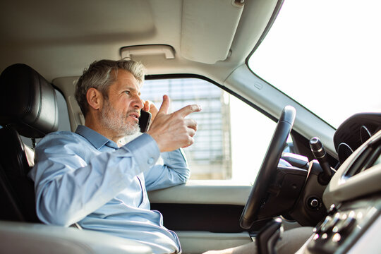 Mature man arguing on phone while driving in car