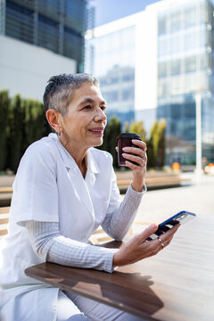 Senior nurse enjoying coffee break outside hospital