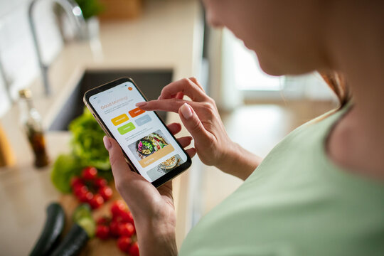 Woman using healthy recipe app in home kitchen