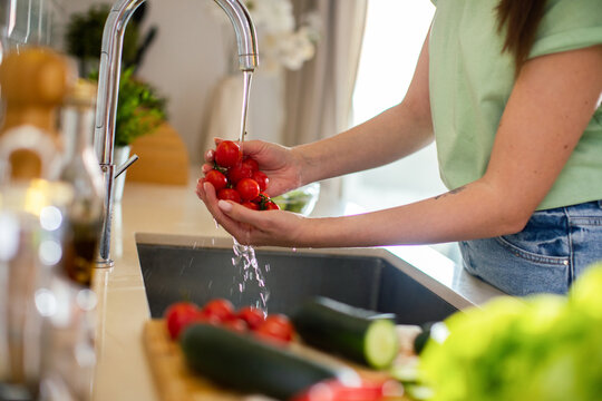 Woman washing cherry tomatoes at kitchen sink