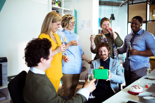 Happy coworkers celebrating a birthday in a modern office