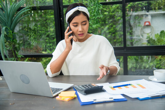 Female freelance reading financial graph charts Planning analyzing marketing data. Business woman using smartphone, laptop on office desk. Hands of young woman working in office firm business info.